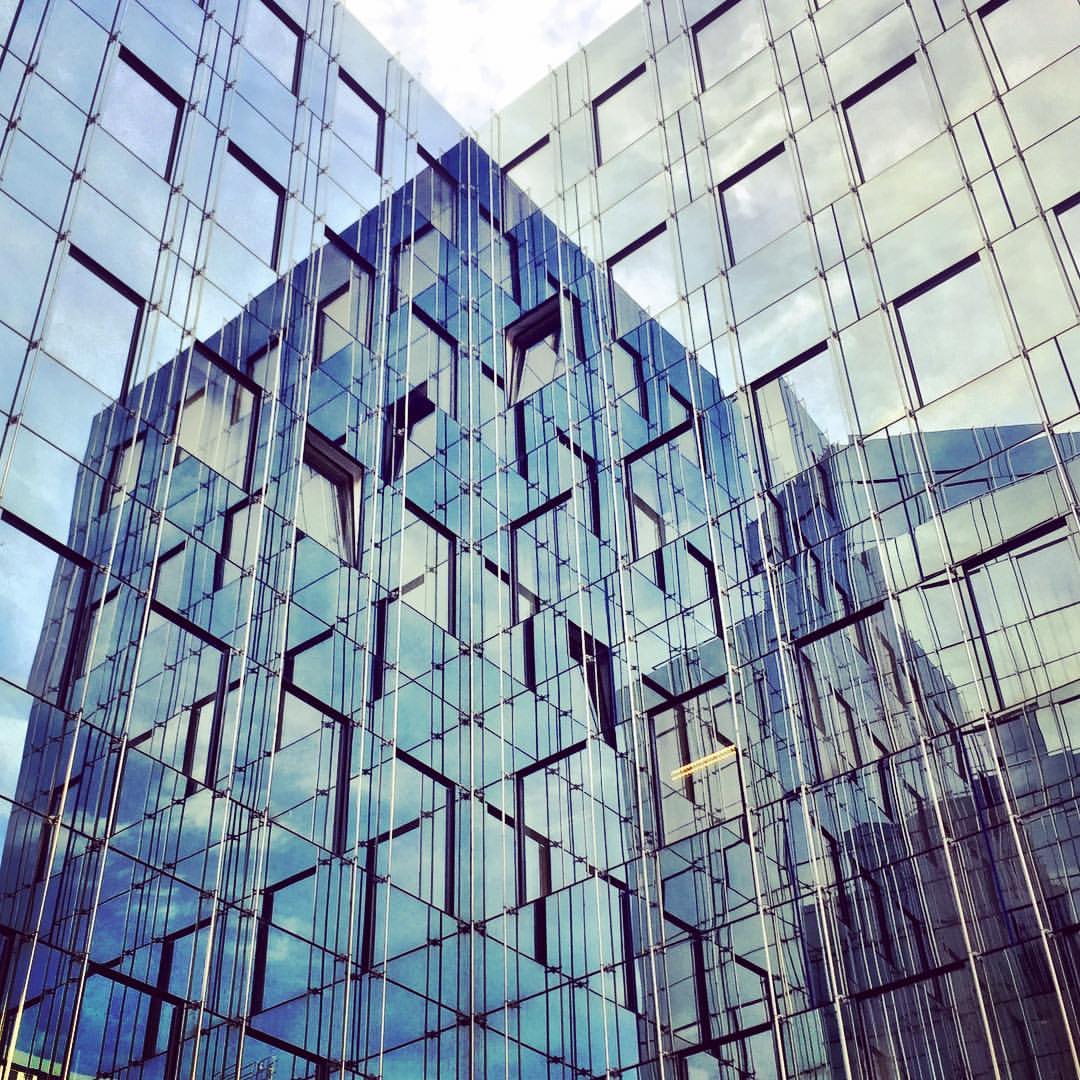  #paracegover A imagem mostra dois prédios cobertos de vidro espelhado, em que um reflete o outro. — at Kaiserin-Augusta-Allee.