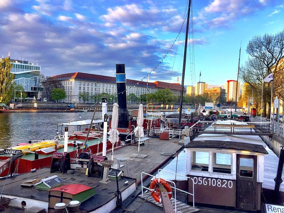 #paracegover Descrição para deficientes visuais: a imagem mostra barcos do porto histórico de Berlin sob um céu que varia do lilás ao turquesa. — at Historischer Hafen Berlin.