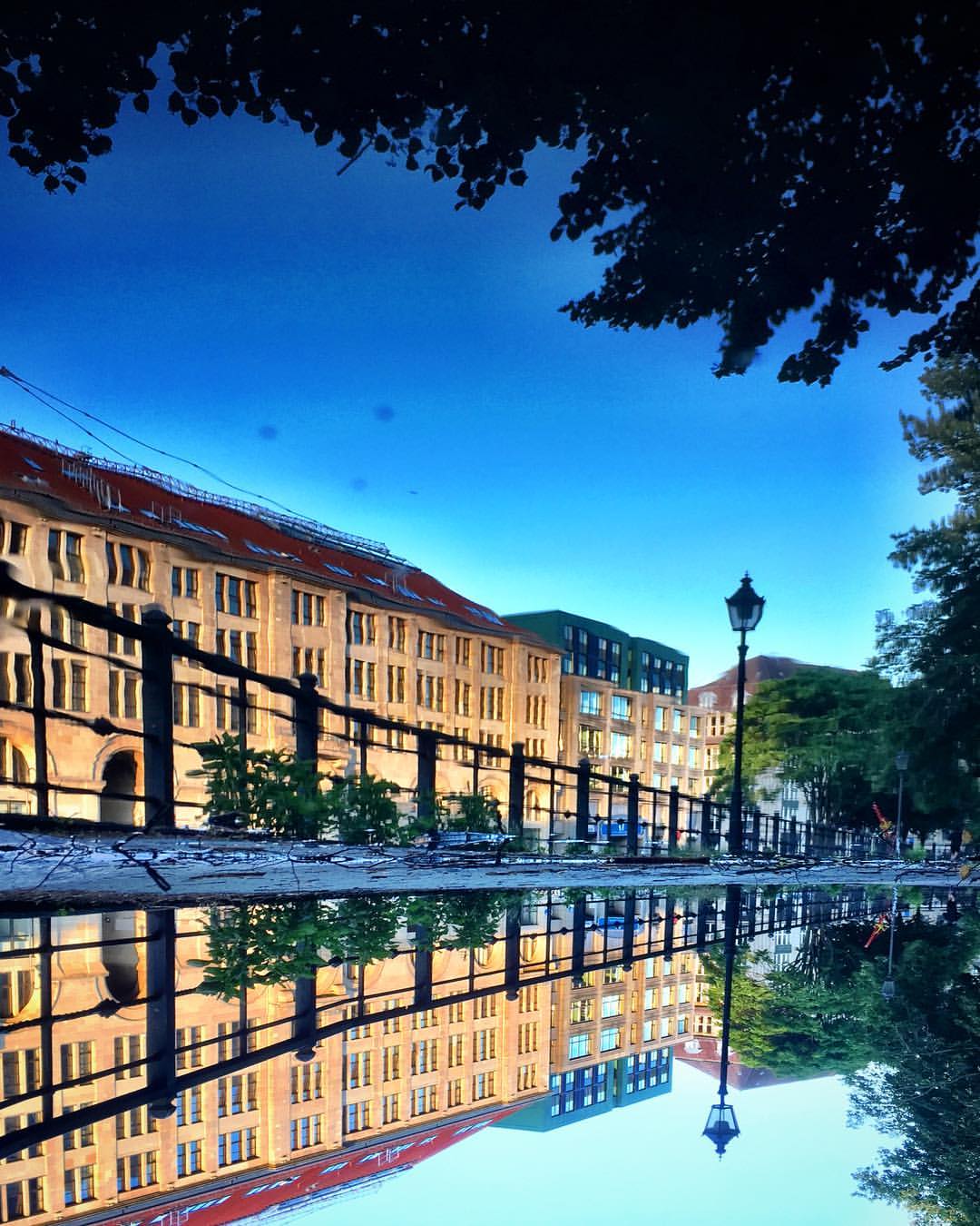 #paracegover Descrição para deficientes visuais: a imagem mostra o casario às margens de um canal do rio Spree refletido numa poça d'água. O dia promete. — at Historischer Hafen Berlin.