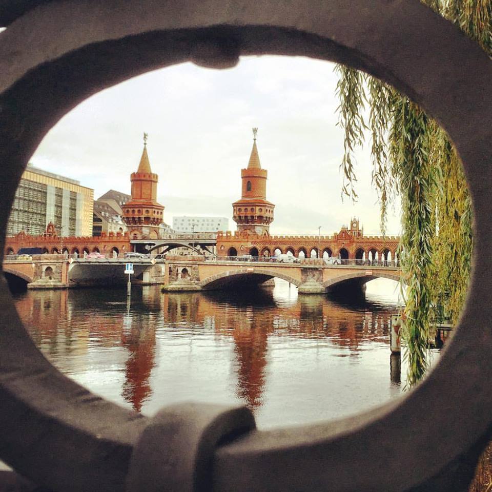 #paracegover Descrição para deficientes visuais: a imagem mostra a belíssima ponte Oberbaum, que liga os bairros Friedrichshain e Kreuzberg, vista do anel da estrtura de ferro da cerca de proteção às margens do rio Spree. O dia está nublado e cheio de mistério no ar... — at Oberbaum Bridge.