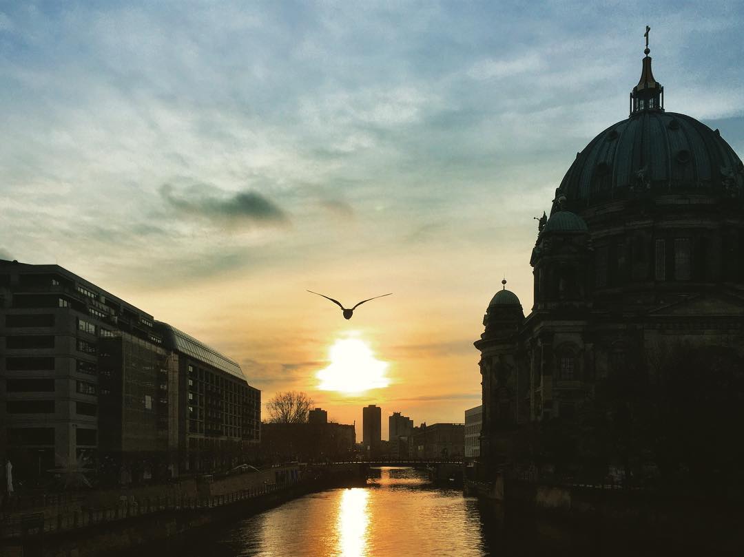 #paracegover Descrição para deficientes visuais: a imagem mostra o sol nascendo às nove horas da manhã em um dia que promete ser tão belo quanto frio. Ao fundo, a silhueta da Catedral de Berlim, à beira do rio Spree. Um pássaro cruza a cena. — at Museum Island.