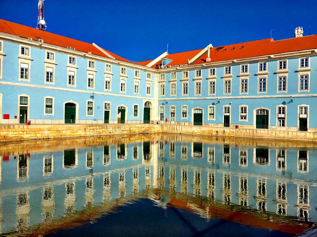 #paracegover Descrição para deficientes visuais: a imagem mostra o prédio da marinha portuguesa, todo azul, refletido no espelho d’água. — at Ribeira das Naus.