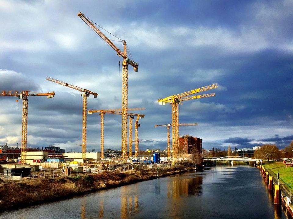 #paracegover Descrição para deficientes visuais: a imagem mostra um canteiro de obras com gruas enormes à beira do rio Spree. O céu, dramático, está refletido na água. — at Spandauer Schifffahrtskanal.