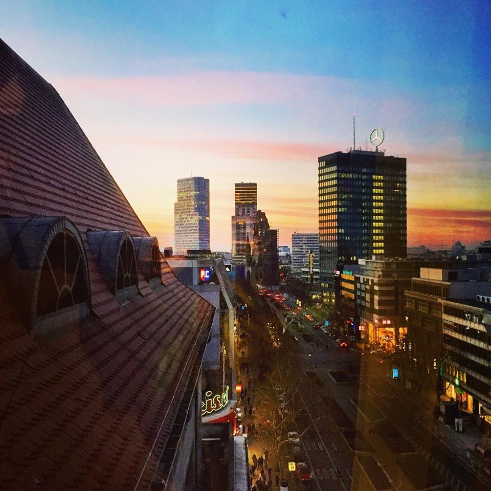 #paracegover Descrição para deficientes visuais: a imagem mostra a rua Kurfürstendamm vista do último andar do prédio da KaDeWe, a loja de departamentos mais tradicional da Alemanha (e a maior, na época em que foi construída, no início do século XX); o por-do-sol está espetacular e ao fundo pode ser ver, além de prédios altos e recentes, os escombros da igreja destruída na Segunda Guerra, a Kaiser-Wilhelm-Gedächtniskirche). -- at KaDeWe