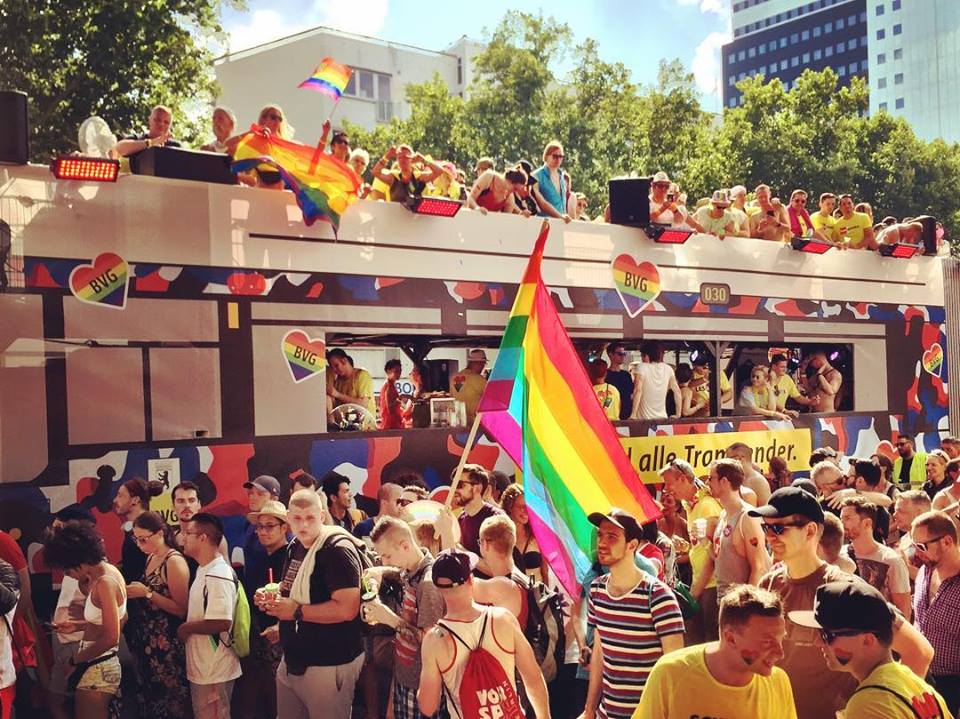 #paracegover Descrição para deficientes visuais: a imagem mostra o trio elétrico da empresa de transportes coletivos de Berlim no Christopher Street Day — a Parada Gay  — as pessoas estão por todos os lados, dançando e portando bandeiras com as cores do arco-íris. — at Nollendorfplatz.