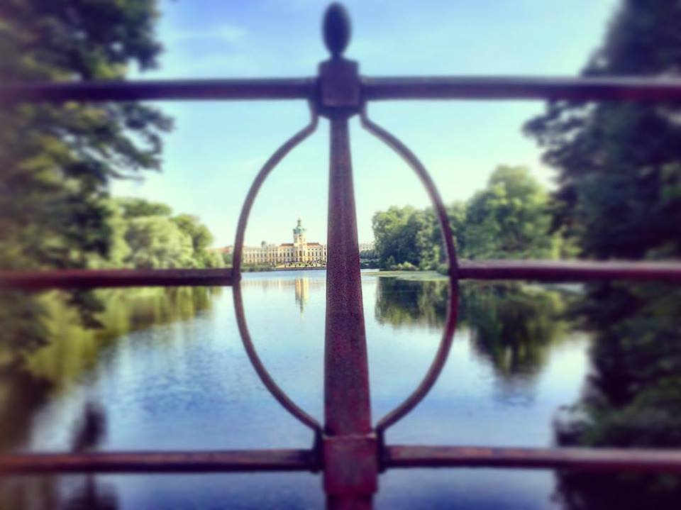  #paracegover Descrição para deficientes visuais: a imagem mostra o Castelo de Charlottenburg em foco, ao fundo. A imagem é refletida no lado e é vista por entre os elementos geométricos do guarda-corpo de uma ponte. — at Schlosspark Charlottenburg.