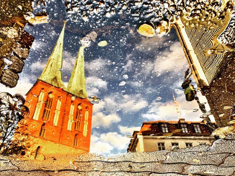 #paracegover Descrição para deficientes visuais: a imagem mostra o reflexo da igreja de São Nicolau, onde começou a cidade de Berlim, refletida numa poça d‘água. — at Nikolaiviertel - Heart of Berlin.