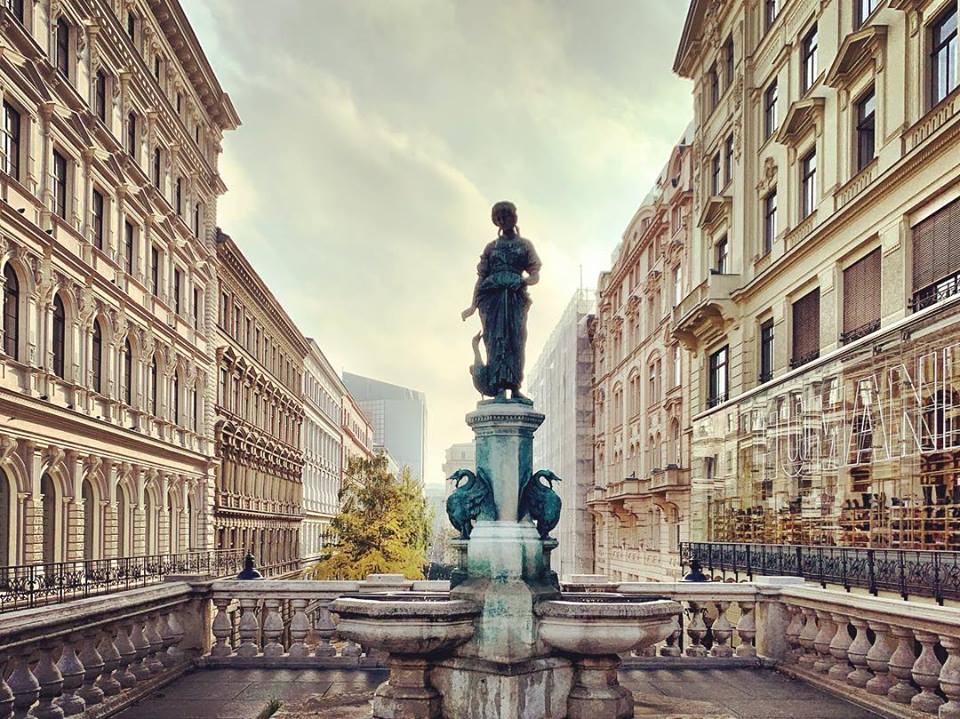 #paracegover Descrição para deficientes visuais: a imagem mostra uma estátua com chafariz, em primeiro plano. Ao fundo, prédios antigos à luz da manhã. — at Mumok, Museum of Modern Art, in Vienna.