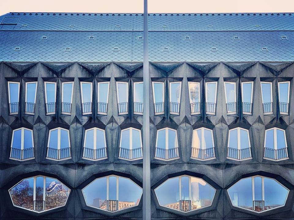 #paracegover Descrição para deficientes visuais: a imagem mostra a fachada de um prédio com os vidros espelhados e janelas com formas geométricas não usuais. — at Alte Münze Berlin.